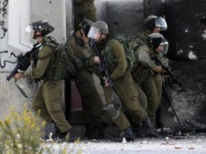 Israeli soldiers take cover behind a wall during clashes with Palestinian protesters in Betunia near the West Bank city of Ramallah on October 11, 2013 (AFP)
