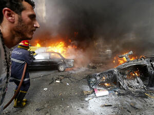A man walks past as a firefighter extinguishing fire at the site of an explosion in Beirut's southern suburb Bir al-Abed (Source: AFP/STR)