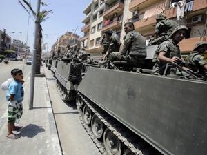 A boy watches Lebanese soliders as they drive between the Sunni and Alawite sections of Tripoli. AFP