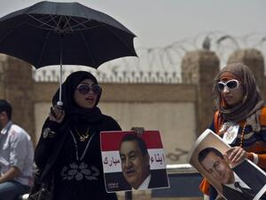 Egyptian female supporters of Egypt's former president Hosni Mubarak, hold portraits of him outside the Egyptian police academy in Cairo. AFP