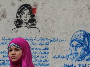 Samira Ibrahim standing next to a graffiti mural that honors her plight. (Image source: "globalpost.com")