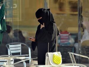A Saudi woman looks at her mobile as she walks through a coffee shop in the capital Riyadh last week. The Saudi government has enacted a switch in the weekend in Saudi, making the working week go from Sunday-Thursday, in line with the majority of the Arab world. (AFP)
