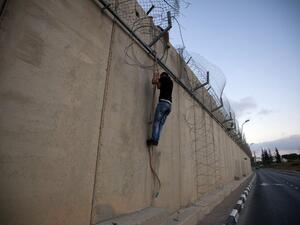  A Palestinian man jumps using a rope over a section of Israel's controversial concrete barrier that separates the West Bank from Jerusalem on August 12, 2013. (AFP)