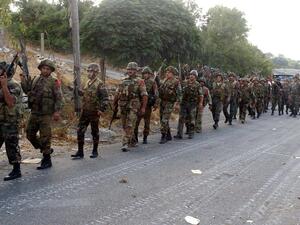 Syrian army soldiers walk on a road during an alleged pursuit of opposition fighters in the Latakia province, western Syria on August 8. (AFP/SANA)