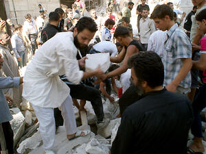 Rescuers and neighboors removes chunks of rubble from a partially collapsed building after a rocketed slammed into the side of a residential block located next to a mosque in the northern city of Aleppo on June 29, 2013. (Source: AFP/JALAL-ALHALABI)