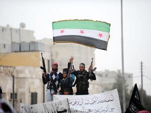 Syrian rebels raise their weapons under a pre-Baath Syrian flag currently used by the opposition during an anti-regime protest in the northern city of Aleppo. (AFP PHOTO/BULENT KILIC)