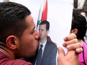 A pro-government supporter kisses a poster of Syrian President Bashar al-Assad.