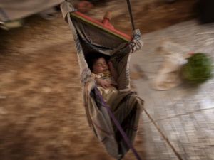 A Syrian refugee baby sleeps in a hammock at the Bab al-Salam refugee camp in Syria's northern city of Azaz on 15 July 2013. (AFP/File)