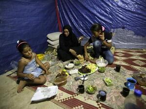 Fatima (C) a Syrian refugee widow, who lost her husband during the fighting in Homs, and her daughters have their Ramadan dinner in their makeshift room in a neighborhood of the Lebanese coastal city of Tripoli (AFP/JOSEPH EID)