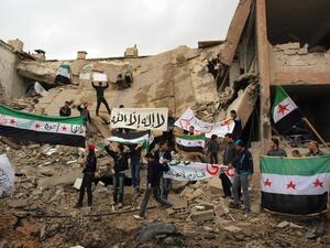 Syrians stand on the wreckage of a building, holding up placards and the Syrian pre-Baath flags during a demonstration against President Bashar Assad in Damascus last week. (AFP PHOTO/HO/SHAAM NEWS NETWORK)
