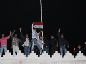 Syrians raise the national flag on the roof of the Qatar Embassy in Damascus on November 12, 2011.