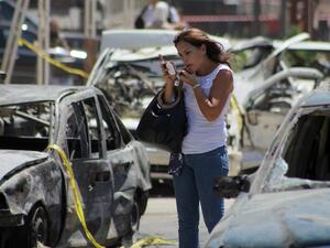 A Lebanese woman puts on make-up near vehicles that were damaged in a bombing outside Al-Taqwa mosque on August 24, 2013 in the northern city of Tripoli. (AFP)