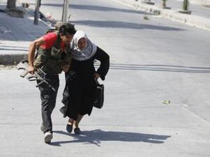 مقاتل من الجيش الحر يساعد امراة على عبور الشارع خلال الاشتباكات في حلب