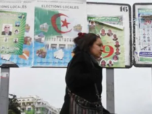 امراة تمر من امام ملصقات انتخابية في الجزائر
