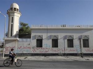 بحريني يمر بدراجة أمام مسجد في قرية دراز غربي المنامة كتبت على جدرانه الخارجية شعارات مناهضة للحكومة البحرينية