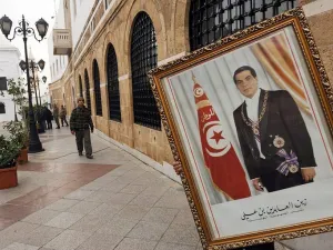 عامل يزيل صورة للرئيس التونسي المخلوع زين العابدين بن علي من مكتب رئيس الوزراء في تونس في كانون الثاني/يناير 2011