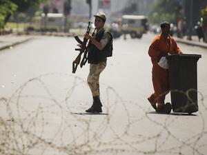 An Egyptian army soldier holds his rifle as he walks by a street cleaner behind a barbed wire checkpoint on a street in Cairo on August 23, 2013. (AFP)