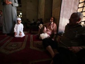 طفل يؤدي مع والده صلاة الجمعة مع والده في الجامع الازهر بالقاهرة