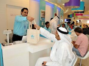 du employee handing a cotton bag to one of the customers as part of du World Environment Day initiative in aims to reduce the use of plastic bags