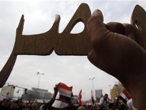 متظاهر مصري يحمل قطعة خشب منحوتة على اسم مصر في ميدان التحرير