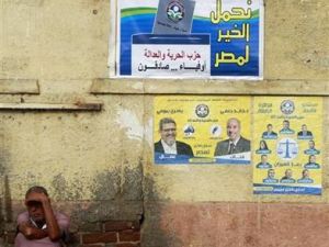 مصري يجلس في شارع أسفل ملصقات انتخابية بالقاهرة