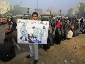 متظاهر مصري يحمل لافتة عليها صورة الناشطة التي تعرضت للضرب وللتعرية من ملابسها من قبل قوات الامن الاسبوع الماضي
