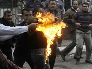 Egyptian members of the Muslim brotherhoods group try to extinguish fire on one of their comrades who he was hit by a molotov cocktail thrown by protesters during clashes in the street that leads to the headquarters of the organization in Cairo on Friday. (Photo: AFP / STR) 