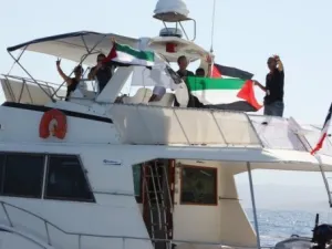ناشطون يلوحون من على متن سفينة الكرامة عند ابحارها من كورسيكا السبت للانضمام الى اسطول الحرية المتوجه الى غزة 
