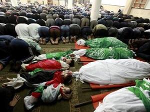 فلسطينيون يصلون بجوار حثامين افراد من عائلة الدلو قبل تشييع جنازتهم في غزة
