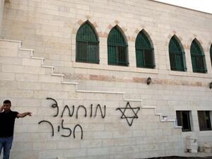 فلسطيني يتحدث في الهاتف من امام مسجد تعرض للتخريب في 5 تشرين الثاني/نوفمبر في الخليل
