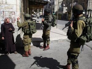 جنود اسرائيليون يوقفون سيدة فلسطينية في الجزء الفلسطيني من مدينة الخليل
