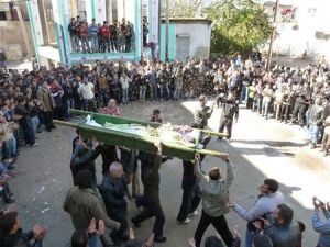 محتجون سوريون ينثرون الأرز فوق جثمان أحد ضحايا العنف في منطقة قرب حمص يوم السبت.