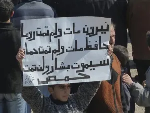 صبي يرفع لافتة تندد بالاسد في بلدة الحولة قرب حمص 
