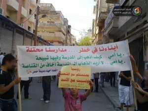 طلاب سوريون يرفعون لافتة أثناء مظاهرة مناهضة لنظام الأسد في حمص ي