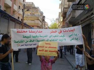 طلاب سوريون يرفعون لافتة أثناء مظاهرة مناهضة لنظام الأسد في حمص ي