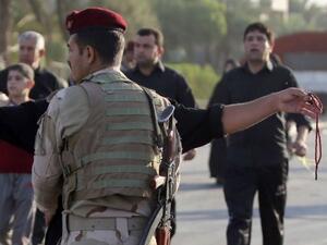 جندي عراقي يفتش المارة في حي الكاظمية شمال بغداد فيما الزوار الشيعة يتوجهون الى ضريح الامام محمد الجواد 
