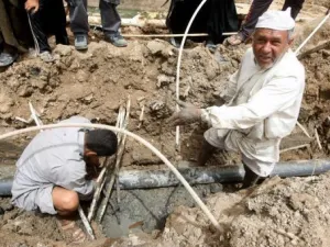 عراقيان يحاولان اصلاح انابيب المياه في الحي الذي يقيمان فيه في بغداد 
