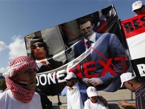 معارض سوري يحمل صورة للقذافي والاسد خلال احتجاج بوسط اسطنبول
