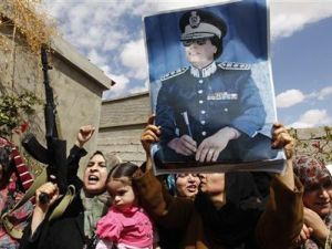 صورة أرشيفية لنساء وأطفال من من الموالين للزعيم الليبي السابق في بني وليد يرفعون أسلحة وصورة للقذافي