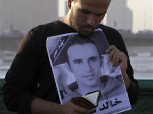 محتج يقرأ القرآن وهو يمسك بصورة خالد خلال الاحتفال بالذكرى الأولى لوفاته في القاهرة 
