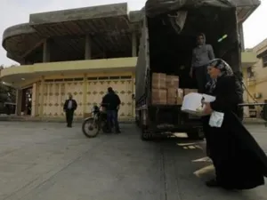 لاجئة سورية هربت من العنف في سوريا تحمل صندوقا من الغذاء شمال لبنان
