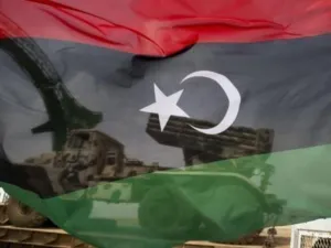 علم للثوار وخلفه عربة محملة بقاذفة صواريخ في اجدابيا