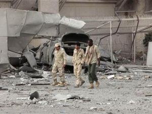  مسؤولون ليبيون يسيرون يوم الاثنين أمام مبنى في مجمع القذافي في باب العزيزية لحقت به أضرار جسيمة جراء هجوم حلف الأطلسي
