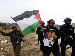 فلسطيني يحمل صورة لمانديلا خلال احتجاج ضد المستوطنات اليهودية في النبي صالح بالضفة الغربية

