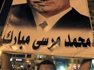 معارض للرئيس المصري محمد مرسي يحمل صورة يشبهه فيها بالرئيس المخلوع حسني مبارك خلال احتجاج في القاهرة
