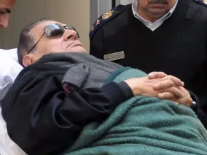 مبارك في سريره بينما يدفعه رجال الشرطة الى داخل المحكمة