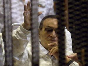 Hosni Mubarak waves from his bed during his retrial which was quickly adjourned (AFP)