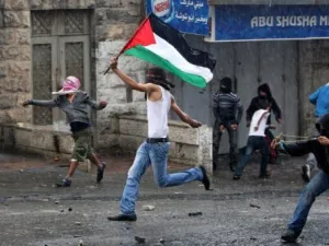  شاب يحمل العلم الفلسطيني ويرشق القوات الاسرائيلية بالحجارة في ذكرى "النكبة" في مخيم شعفاط للاجئين الفلسطينيين
