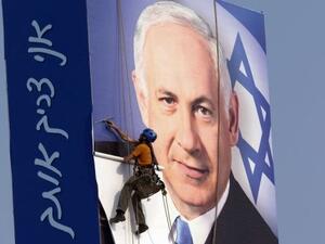 رجل يقوم بتثبيت ملصق انتخابي لرئيس الوزراء الاسرائيلي بنيامين نتانياهو