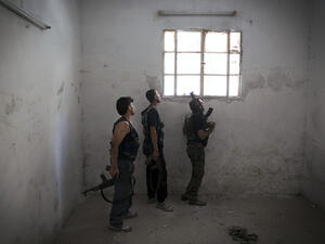 Rebel fighters look at the pro-government forces' positions through a window as they hold a position in an empty room in the Salaheddine district of the northern Syrian city of Aleppo, on July 9, 2013. (Source: AFP/JM LOPEZ)